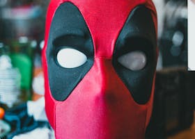 Close-up of a Deadpool mask on a wooden surface indoors, perfect for superhero fans.